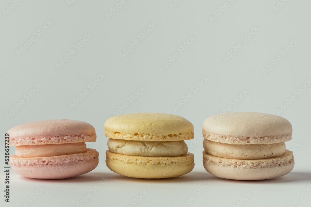 Set of multicolored macaroons lined in a row on the white background. Traditional French dessert. St Valentine's Day. Yellow, beige and pink macaroons Set of multicolored macaroons lined in a row on the white background. Traditional French dessert. St Valentine's Day. Yellow, beige and pink macaroons