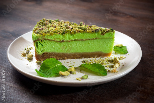 Pistachio cheesecake portion with matcha flavor and mint. A bright green piece of dessert on a plate.