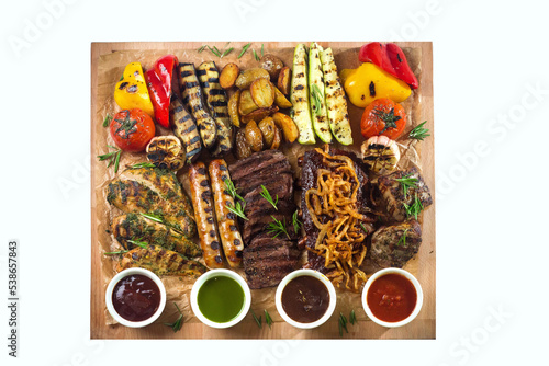 A board with grilled appetizers and sauces. Grilled vegetables and meat snacks: sausages, chicken fillets, pork and beef steaks.