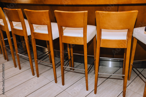 Wooden vintage chairs stand in a row indoors.
