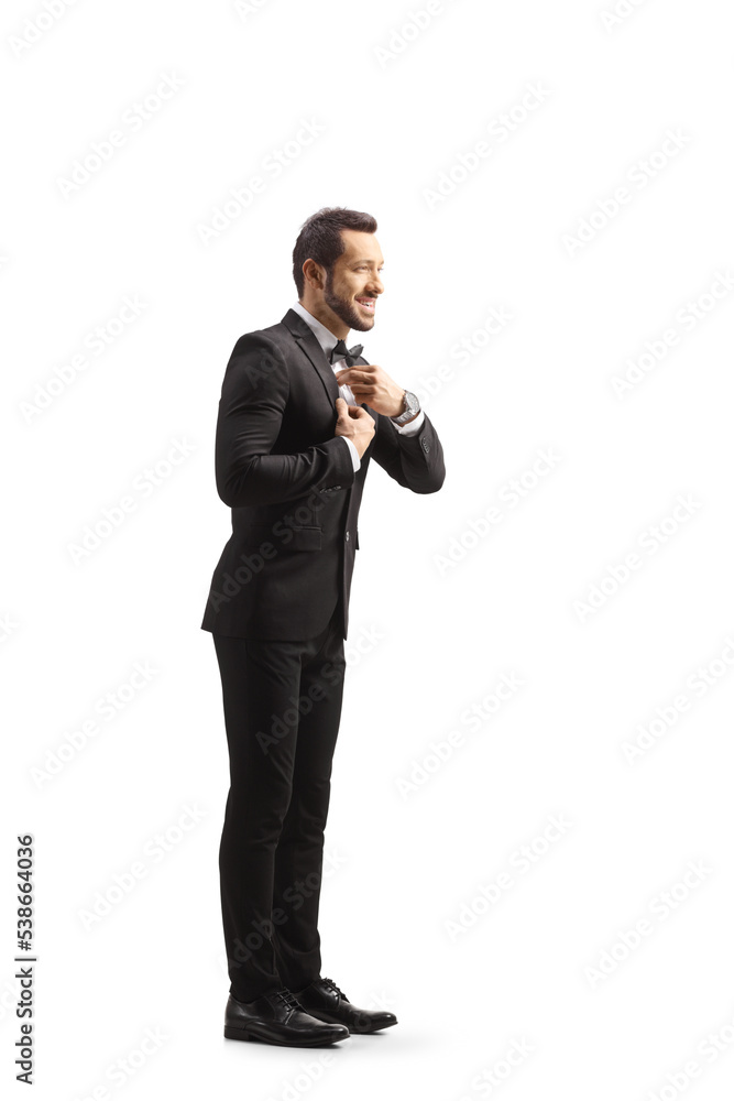 Naklejka premium Full length profile shot of a young elegant man getting ready and fixing his bow tie