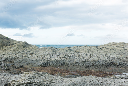 rocky seashore made of columnar granite, hardened lava, resembling scales or cobblestone pavement, coast of Kunashir island photo