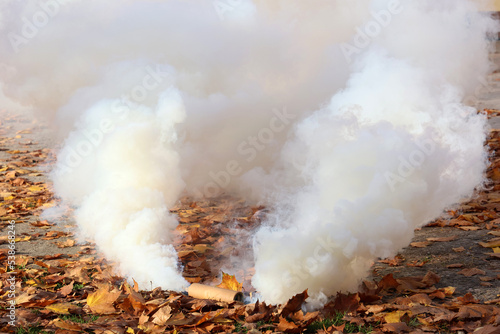 Mocny biały dym leci z wojskowej świecy dymnej.  photo
