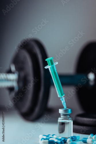 dumbbells, syringe with needle, pills and vial with steroids. illegal doping in sport concept