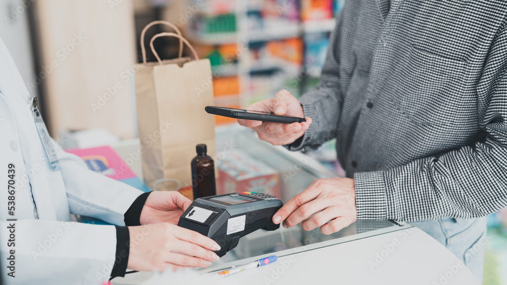 An adult customer stands to pay at the pharmacy counter.Business, pharmacy, professional health care An adult customer stands to pay at the pharmacy counter.Business, pharmacy, professional health care