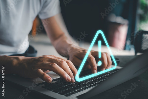 Businessman using computer laptop with triangle caution warning sing for notification error and maintenance concept.