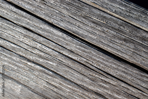 Diagonal pattern of old boards. Fibers of old wood close-up. Cracks on gray boards, top view.