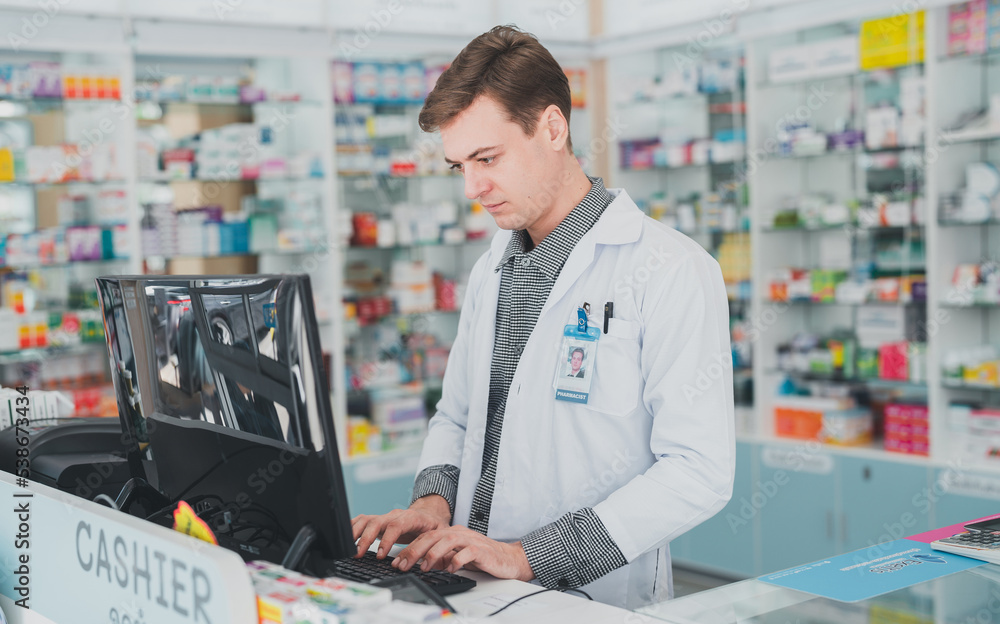 male pharmacist working at hospital.male doctor working at a pharmacy.male chemist The pharmacy works at the computer counter.Business, pharmacy, professional health care.