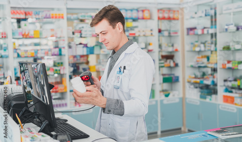 male pharmacist working at hospital.male doctor working at a pharmacy.male chemist The pharmacy works at the computer counter.a pharmacist holding a bottle of pills.