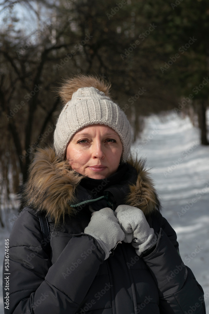Girl in winter clothes on the background of the forest in winter.