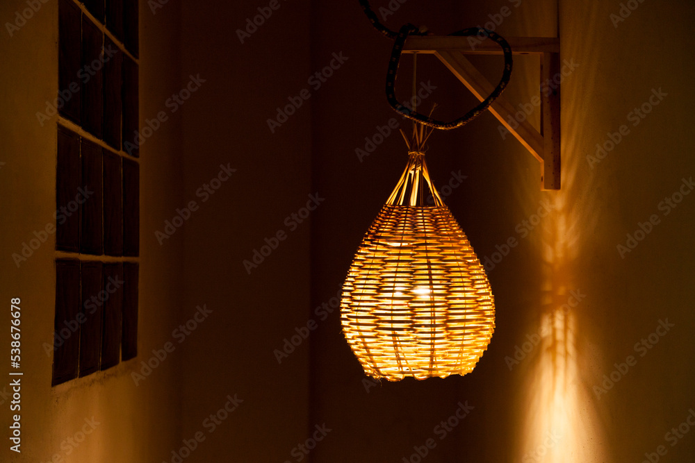 Pendant luminaire for outdoor area with yellow light. Handmade lamp made of straw. Luminaire concept. Home sweet home concept.