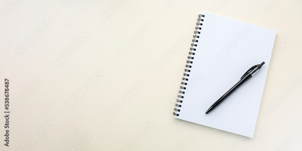 Notebook on a spiral on a plain beige background. Blank white sheets in a note. Flat lay, banner, top view, copy space Notebook on a spiral on a plain beige background. Blank white sheets in a note. Flat lay, banner, top view, copy space