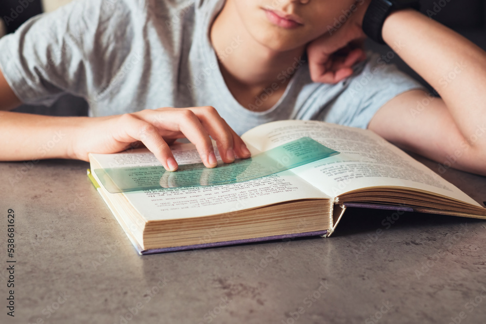 Reading tools for dyslexia. Child reading book using colorful ruler overlay strips. Education, learning disability, reading difficulties concept Reading tools for dyslexia. Child reading book using colorful ruler overlay strips. Education, learning disability, reading difficulties concept