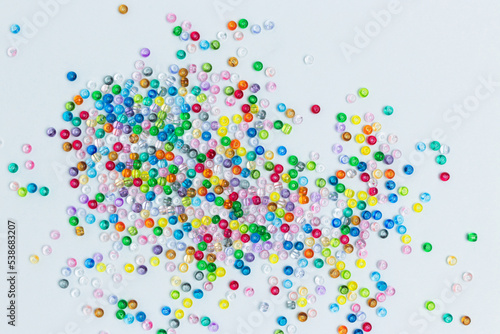 Colorful beads scattered on a blue background. Equipment for handmade accessories.