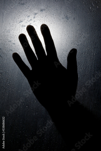 silhouette of a hand on a dark glass window