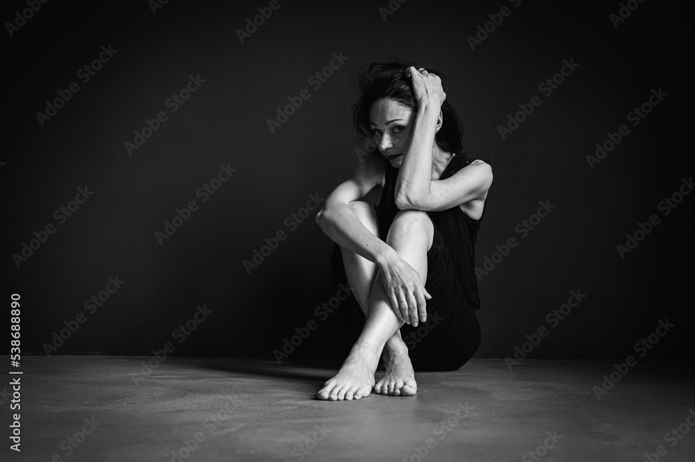 Black and white classic photo, young pretty girl sitting on the floor, pensive, thinking, depression, dark background, low key Black and white classic photo, young pretty girl sitting on the floor, pensive, thinking, depression, dark background, low key