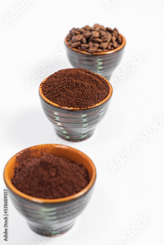 Three cups of coffee beans, ground coffee and cocoa for comparison.