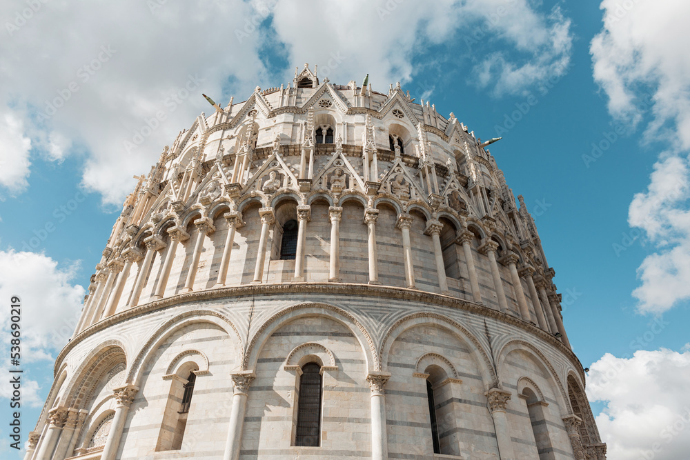 Beautiful Romanesque architecture facade of a cathedral in the European city of Pisa, Italy. Amazing ancient building on a sunny day with clouds