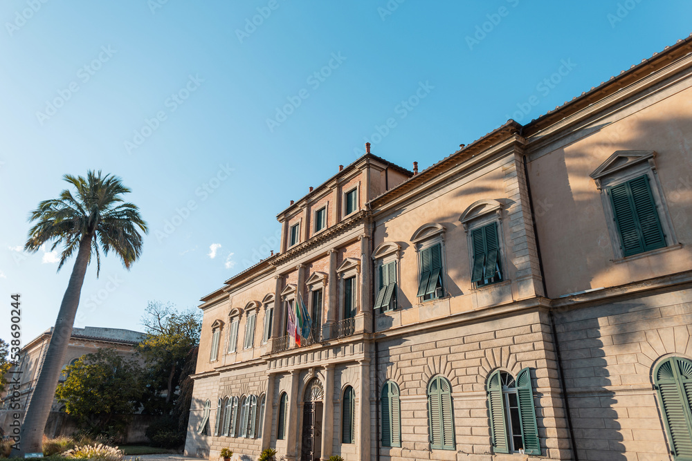 Beautiful vintage building with a palm tree at sunset in Italy. Travelling and relaxing in a European town in Pisa, Italy