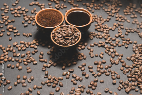 Set of three cups of coffee beans, ground and drink on a black background.