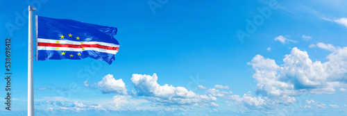 Cape Verde flag waving on a blue sky in beautiful clouds - Horizontal banner