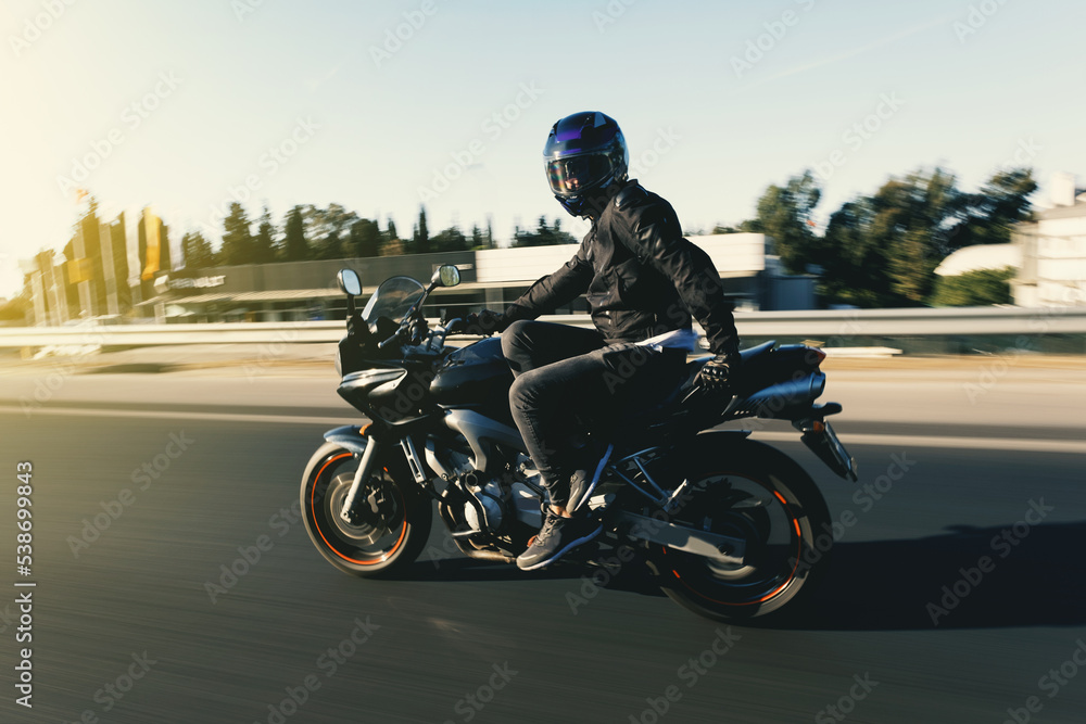 Side view of a motorcycle rider riding race motorcycle like sitting on a chair on the highway with motion blur.