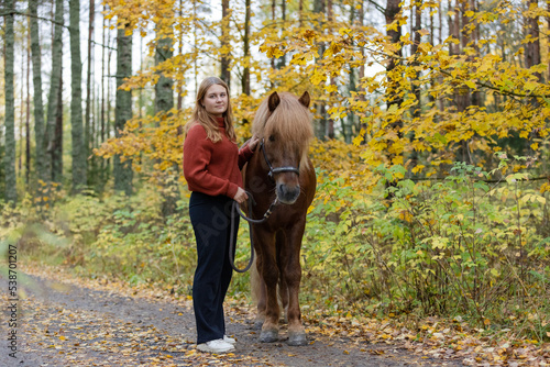 Young female equestrian posing with Icelandic horse in in autumn scenery © AnttiJussi