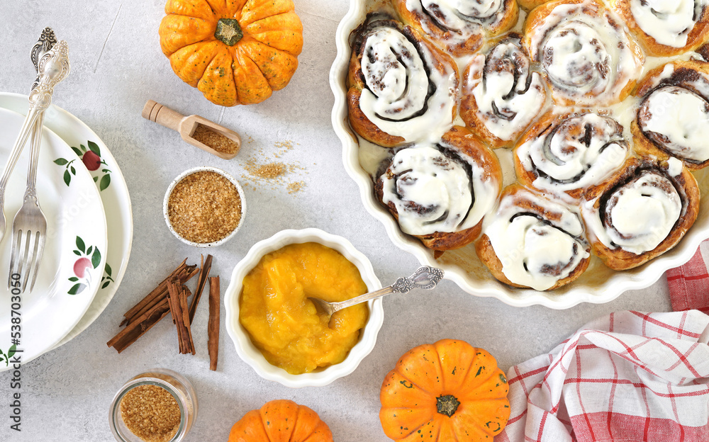 Homemade Pumpkin cinnamon rolls with cream cheese in a baking dish, flat lay, top veiw. Seasonal autumn homemade pastry - cinnabons for breakfast or holidays. top view Homemade Pumpkin cinnamon rolls with cream cheese in a baking dish, flat lay, top veiw. Seasonal autumn homemade pastry - cinnabons for breakfast or holidays. top view