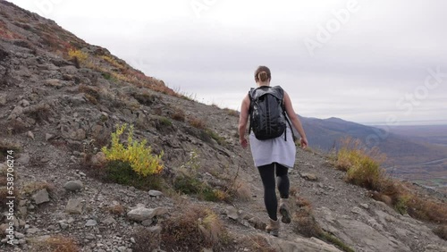 woman hiking while wearing backbag in the mountains cloudy weather ponytail mountaineering autumn time good sweat workout