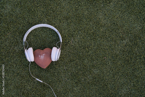 stone hearts with headphones on grass background