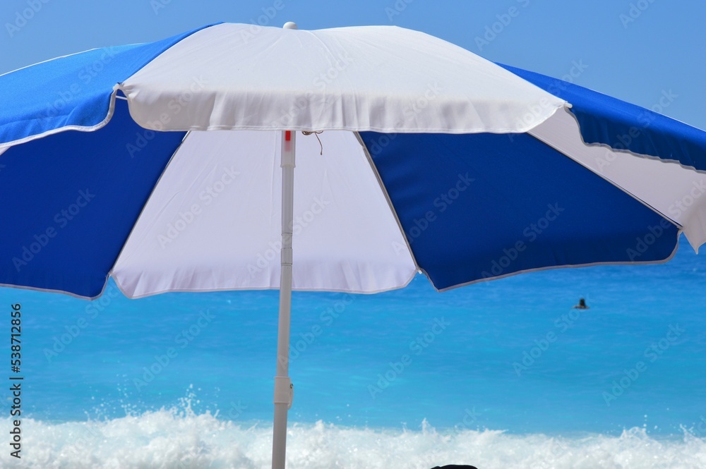 A blue and white umbrella against the turquoise blue sea