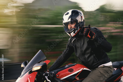 Side view of a motorcycle rider riding red race motorcycle on the highway with motion blur. photo