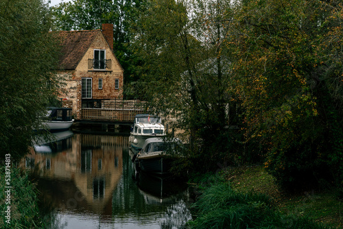House by the river, reflections in the water, autumn forest