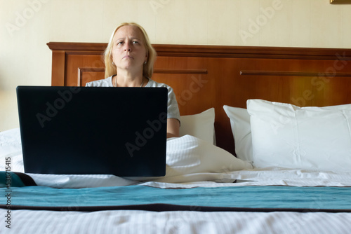 Blonde woman in bed with a laptop.