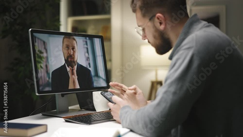 Two caucasian males having videochat and discussing business decisins, young male checking infornation on smartphone application. photo