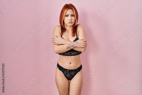 Young caucasian woman wearing lingerie over pink background shaking and freezing for winter cold with sad and shock expression on face