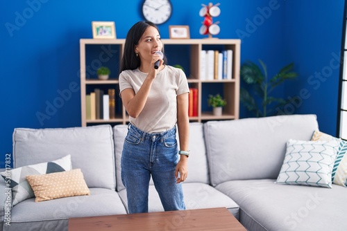 Young beautiful hispanic woman smiling confident singing song at home