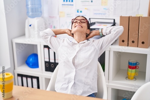 Young beautiful hispanic woman business worker relaxed with hands on head at office