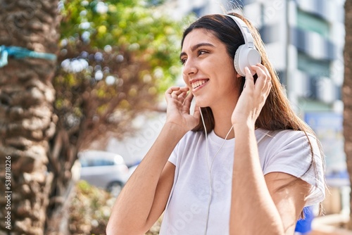 Young beautiful woman smiling confident listening to music at street