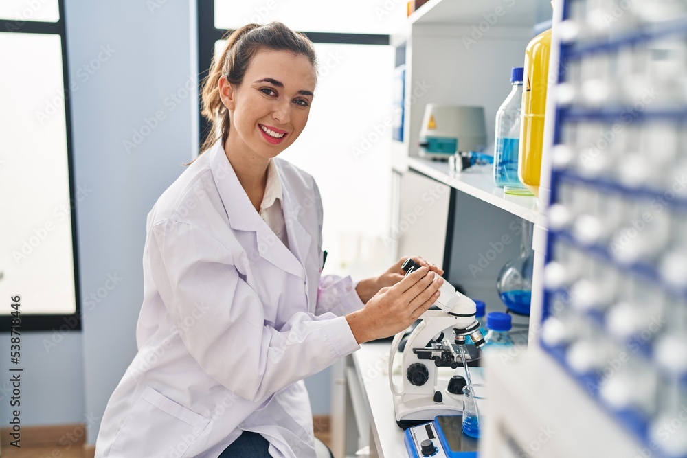 Young woman wearing scientist uniform using microscope at laboratory Young woman wearing scientist uniform using microscope at laboratory