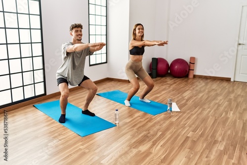 Young hispanic sporty couple smiling happy training legs exercise at the sport center.