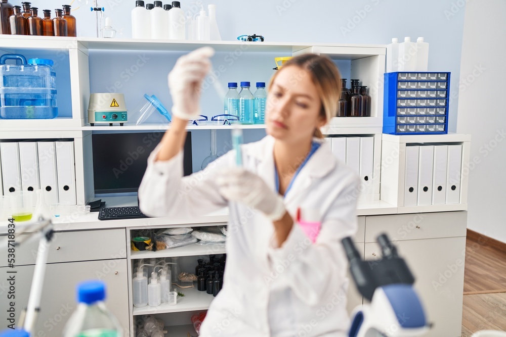 Young hispanic woman scientist pouring liquid on test tube at laboratory Young hispanic woman scientist pouring liquid on test tube at laboratory