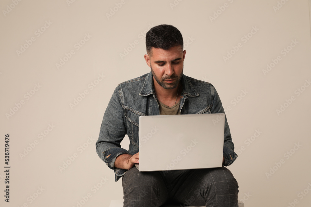 Handsome young Indian guy working online from home, using laptop. Mock-up.