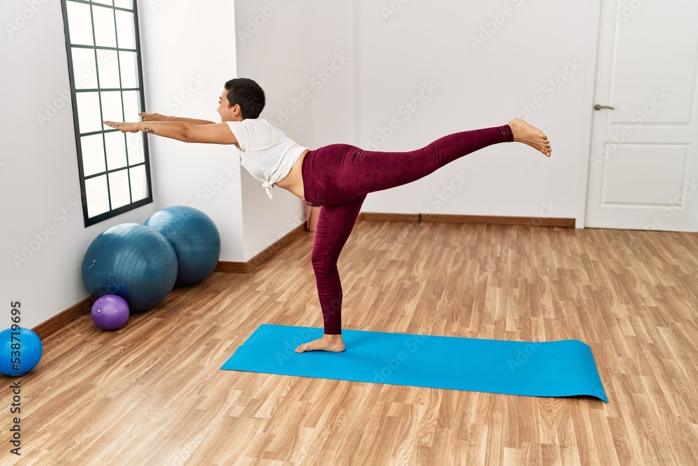 Young hispanic woman smiling confident training yoga at sport center