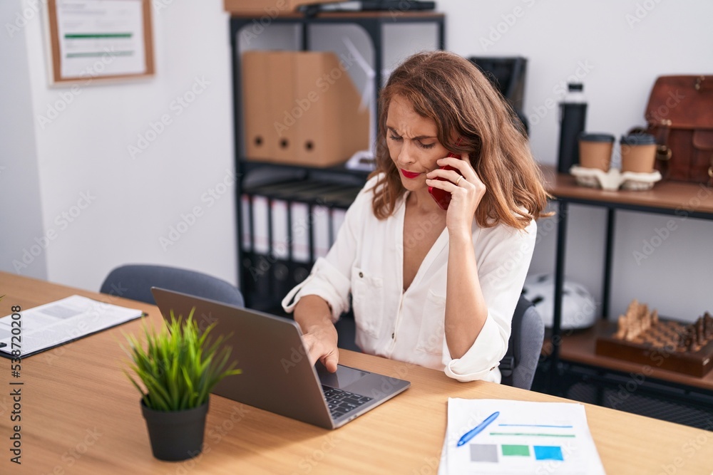 Young beautiful hispanic woman business worker talking on smartphone using laptop at office Young beautiful hispanic woman business worker talking on smartphone using laptop at office
