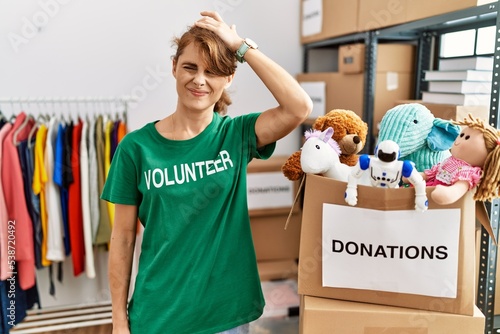 Beautiful caucasian woman wearing volunteer t shirt at donations stand confuse and wondering about question. uncertain with doubt, thinking with hand on head. pensive concept.