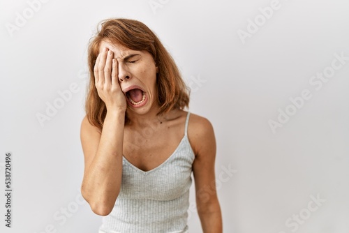 Beautiful caucasian woman standing over isolated background yawning tired covering half face, eye and mouth with hand. face hurts in pain.