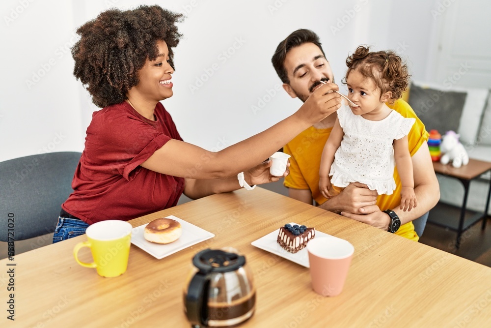 Fototapeta premium Couple and daughter having breakfast sitting on table at home