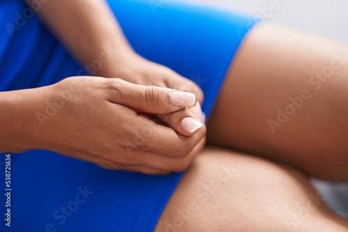 Young beautiful latin woman sitting on sofa with hands together at street