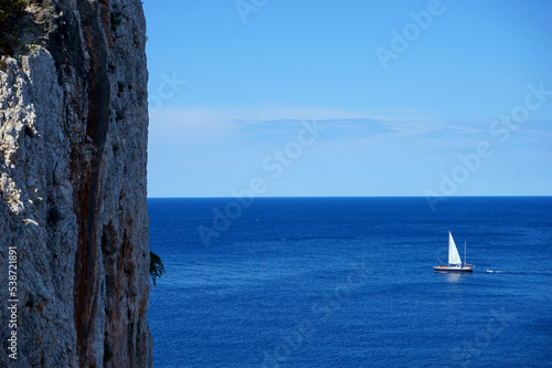 sailboat beyond steep cliff